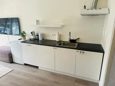 a kitchen with white cabinets and a sink at Hello Noordwijk - Zomerhuis Quarles van Uffordstraat in Noordwijk aan Zee