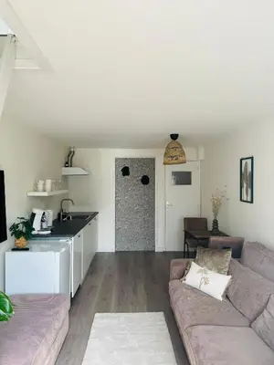 a living room with a couch and a kitchen at Hello Noordwijk - Zomerhuis Quarles van Uffordstraat in Noordwijk aan Zee