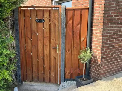 a wooden gate on the side of a brick building at Snijders cottage in Noordwijkerhout