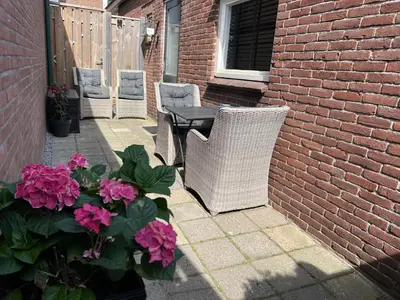 a patio with two chairs and a table and flowers at Snijders cottage in Noordwijkerhout