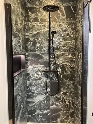 a shower in a bathroom with a stone wall at Amsterdam Grachtenappartement in Amsterdam