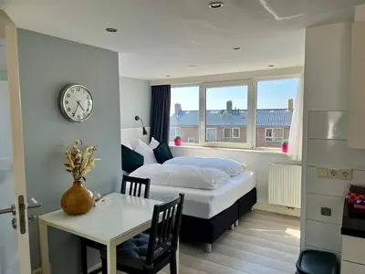 a bedroom with a bed and a table and a clock at Hammond Studio Apartments in Zandvoort