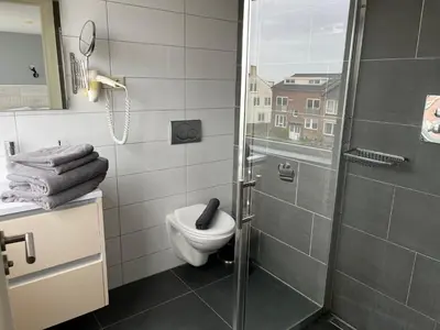 a bathroom with a toilet and a glass shower at Hammond Studio Apartments in Zandvoort