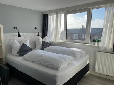 a white bed in a room with a window at Hammond Studio Apartments in Zandvoort