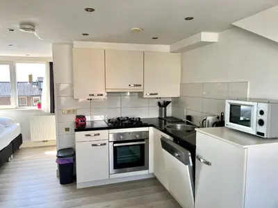 a kitchen with white cabinets and a microwave at Hammond Studio Apartments in Zandvoort