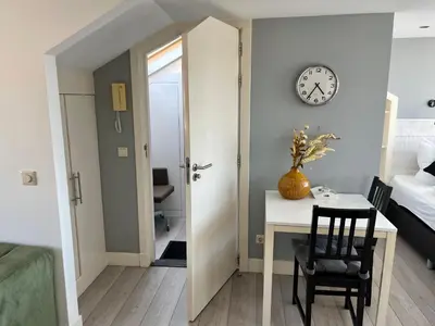 a room with a table and a clock on the wall at Hammond Studio Apartments in Zandvoort