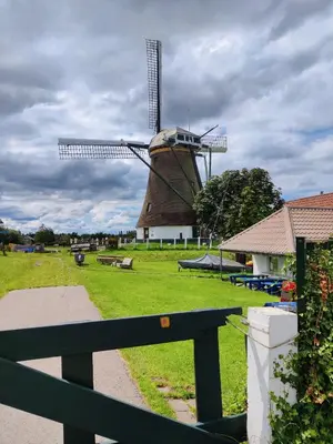 a windmill in the middle of a field with a fence at Park De Driesprong in Nieuwveen