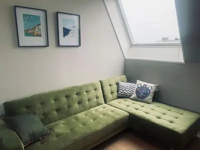 a green couch in a room with a window at Have a nice stay! - Main Street beachapartment, beach 150 meters in Noordwijk aan Zee