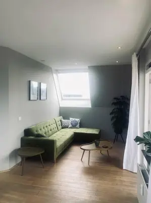 a living room with a green couch and a window at Have a nice stay! - Main Street beachapartment, beach 150 meters in Noordwijk aan Zee