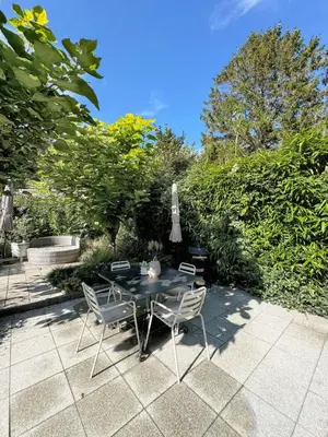 a table with chairs and an umbrella on a patio at Duin Cottage Bergen in Bergen