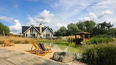 a house with two lawn chairs in front of a pond at Duinvilla Noordwijk in Noordwijk
