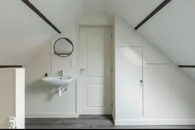 a white bathroom with a sink and a shower at Zomerhuis Het Hoekje in Egmond aan Zee