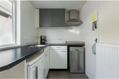 a white kitchen with a sink and a dishwasher at Zomerhuis Het Hoekje in Egmond aan Zee