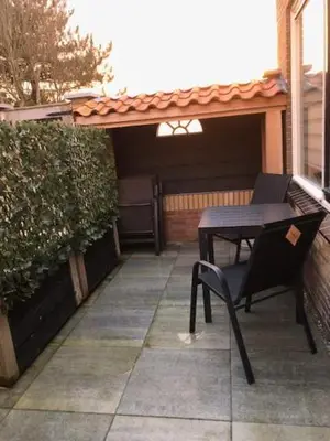 a patio with a black table and chairs on a patio at Zomerhuis Het Hoekje in Egmond aan Zee