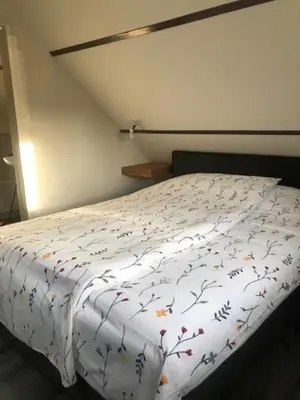 a bedroom with a white bed with flowers on it at Zomerhuis Het Hoekje in Egmond aan Zee