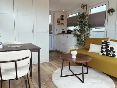 a living room with a yellow couch and a table at Tiny lake houses near the beach and centre by Weltevreden Experience in Zeewolde