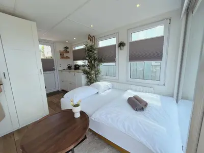 a bedroom with a white bed and a wooden table at Tiny lake houses near the beach and centre by Weltevreden Experience in Zeewolde