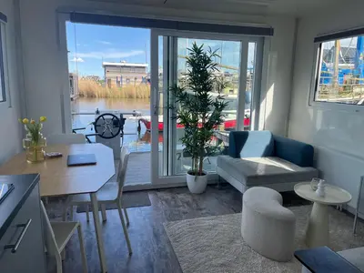 a living room with a view of the water at Tiny lake houses near the beach and centre by Weltevreden Experience in Zeewolde
