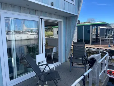 a balcony with two chairs and a table on a boat at Tiny lake houses near the beach and centre by Weltevreden Experience in Zeewolde
