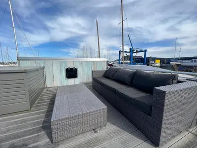 a couch sitting on the deck of a boat at Tiny lake houses near the beach and centre by Weltevreden Experience in Zeewolde