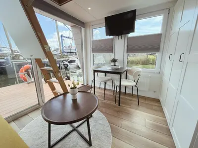 a living room with a table and chairs and a television at Tiny lake houses near the beach and centre by Weltevreden Experience in Zeewolde