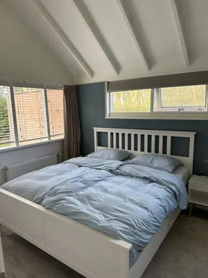 a white bed in a bedroom with two windows at Rekerlanden 104 in Schoorldam