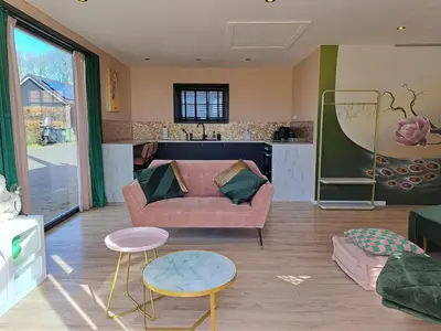 a living room with a couch and tables and a kitchen at Hooischuur Wakker in Eemnes
