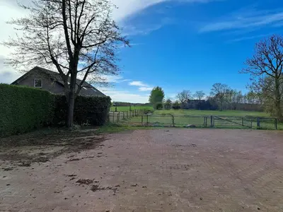 a yard with a fence and a tree and a house at Hooischuur Wakker in Eemnes