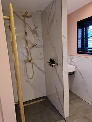 a shower in a bathroom with a marble wall at Hooischuur Wakker in Eemnes