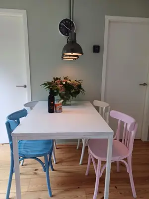 a dining room table with pink and blue chairs at Vrije Vogels tuin met privacy in Warmenhuizen