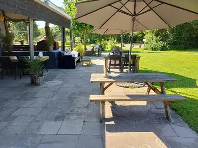 two picnic tables and an umbrella on a patio at Vrije Vogels tuin met privacy in Warmenhuizen