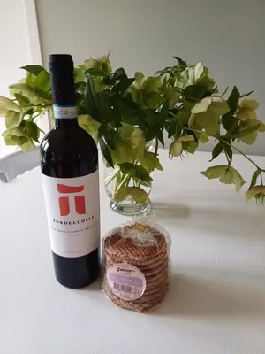 a bottle of wine next to a vase with a plant at Vrije Vogels tuin met privacy in Warmenhuizen