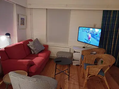 a living room with a red couch and a tv at Vrije Vogels tuin met privacy in Warmenhuizen