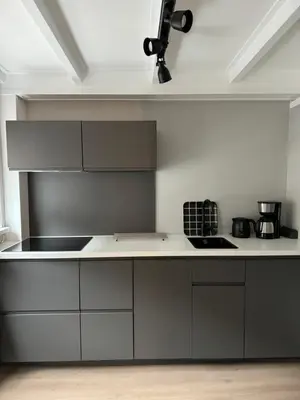 a kitchen with gray cabinets and a white counter top at Hello Katwijk - Zomerhuis Paul Krügerstraat 3 in Katwijk aan Zee