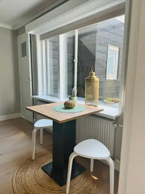 a table and two stools in a room with a window at Hello Katwijk - Zomerhuis Paul Krügerstraat 3 in Katwijk aan Zee