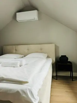 a bed with white sheets and a light above it at Hello Katwijk - Zomerhuis Paul Krügerstraat 3 in Katwijk aan Zee