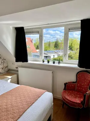 a bedroom with a bed and a chair and windows at The Grutto, private apartment 25 min from city center in Amsterdam