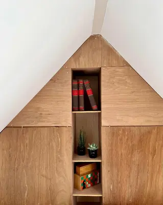a book shelf with books in the shape of a triangle at The Grutto, private apartment 25 min from city center in Amsterdam