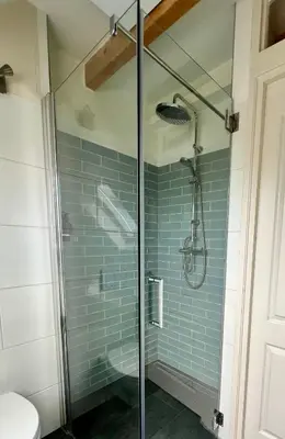 a glass shower in a bathroom with blue tiles at The Grutto, private apartment 25 min from city center in Amsterdam