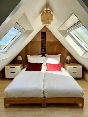 a bedroom with a large bed with two windows at The Grutto, private apartment 25 min from city center in Amsterdam