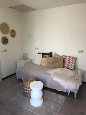 a bedroom with a bed and a couch and a table at Vakantiehuis in Katwijk aan zee in Katwijk aan Zee