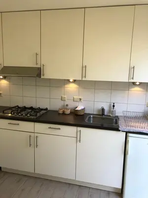 a kitchen with white cabinets and a sink at Vakantiehuis in Katwijk aan zee in Katwijk aan Zee