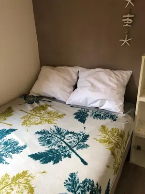 a bed with a green and white blanket on it at Vakantiehuis in Katwijk aan zee in Katwijk aan Zee