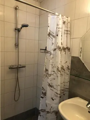 a bathroom with a shower curtain and a sink at Vakantiehuis in Katwijk aan zee in Katwijk aan Zee