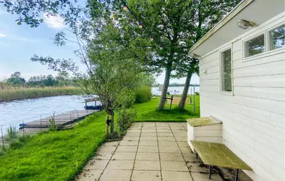 a house with a bench next to a river at Lakehouse Reeuwijk in Reeuwijk