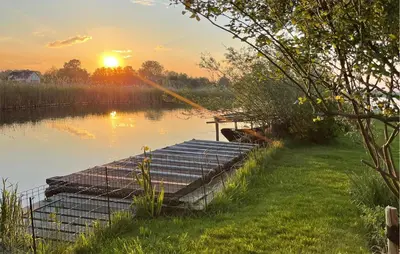 a dock on a lake with the sunset in the background at Lakehouse Reeuwijk in Reeuwijk