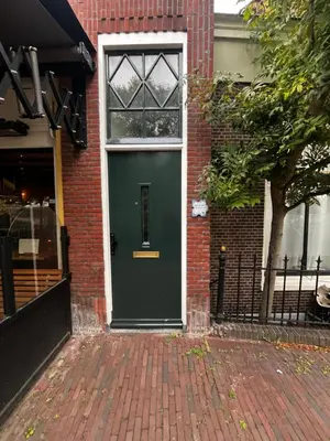 a green door on the side of a brick building at Apartement hotel Stays by ADM in Leiden