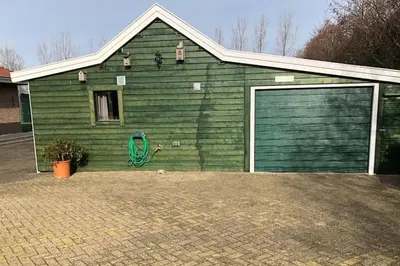 a green house with a garage with at Have a nice stay! - Vakantiehuis 't Klavertje in Noordwijk