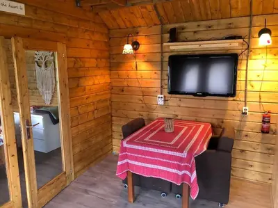 a dining room with a table and a tv in a cabin at Have a nice stay! - Vakantiehuis 't Klavertje in Noordwijk