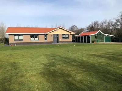 a house with a large grass field in front of it at Have a nice stay! - Vakantiehuis 't Klavertje in Noordwijk